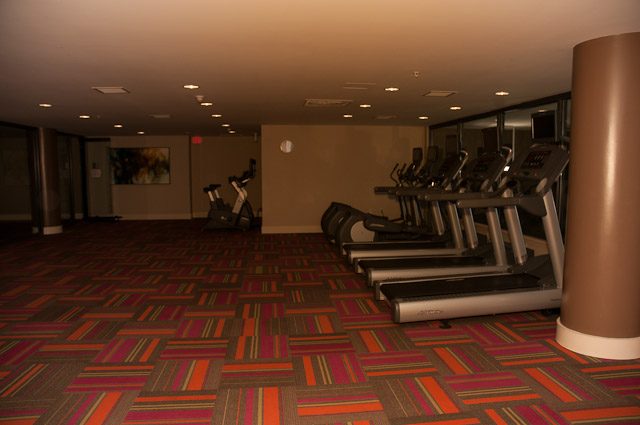 Fitness room with treadmills and exercise bikes, colorful patterned carpet. - 501-150 Athletes Way, Vancouver West Side