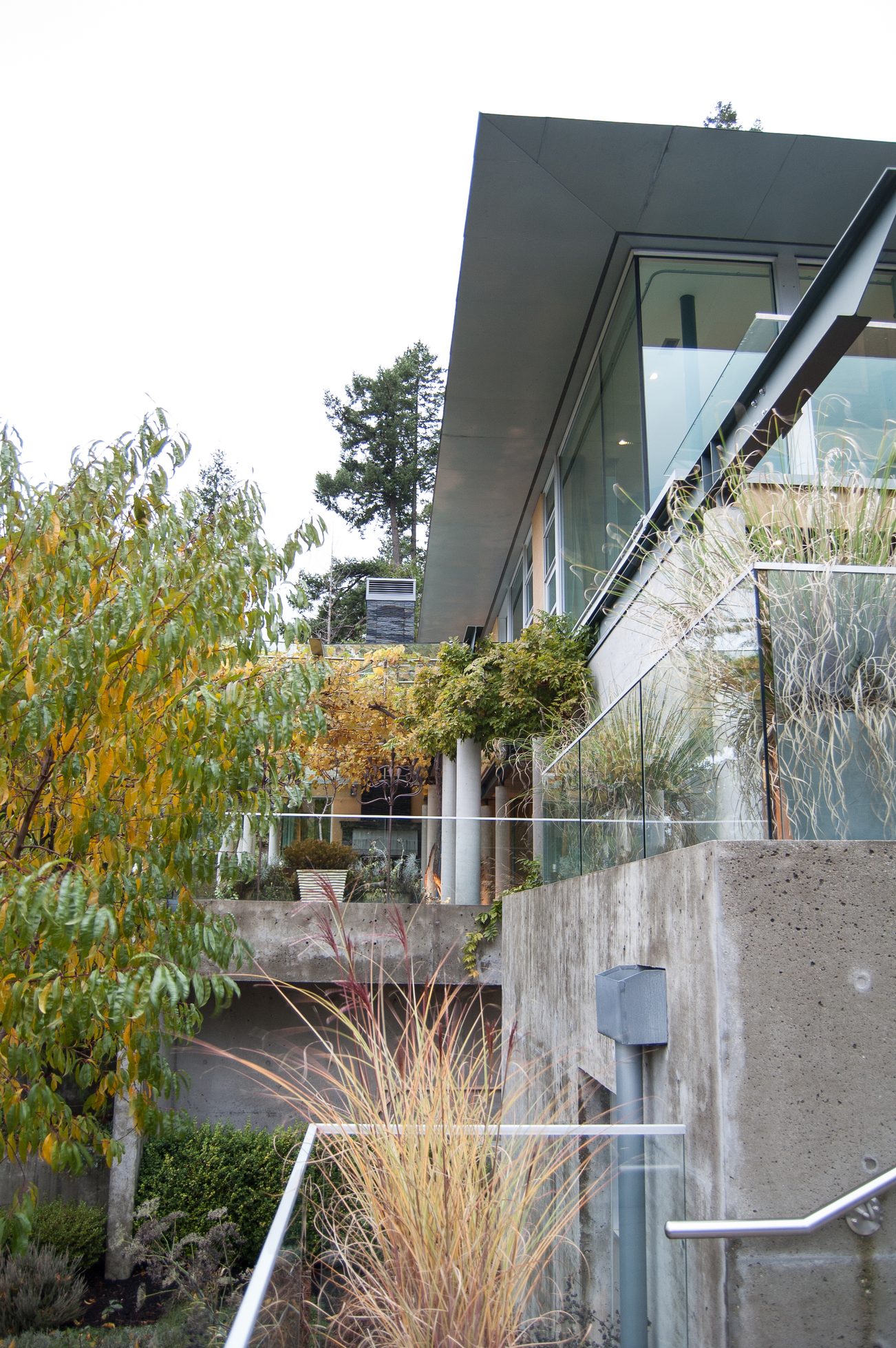 Modern living room with glass walls and concrete accents. - 4454 Regency Place, West Vancouver