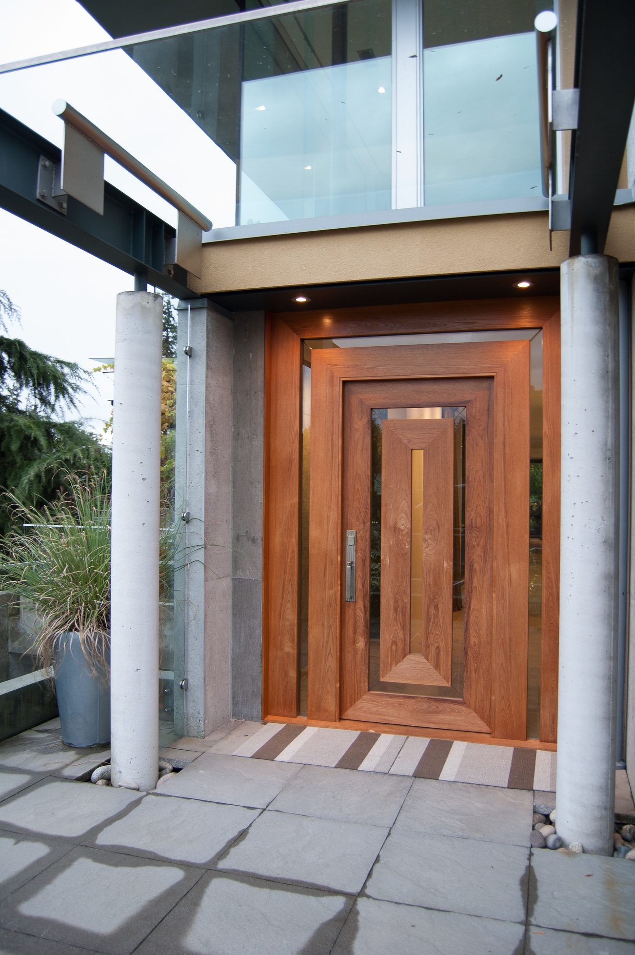 Modern entryway with a wooden door and stone flooring. - 4454 Regency Place, West Vancouver