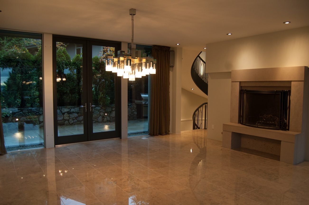 Spacious living room with marble floors, large windows, and a modern chandelier. - 4454 Regency Place, West Vancouver