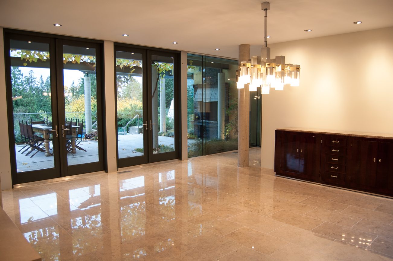 Bright dining area with glossy marble countertops and large glass doors leading to a patio. - 4454 Regency Place, West Vancouver