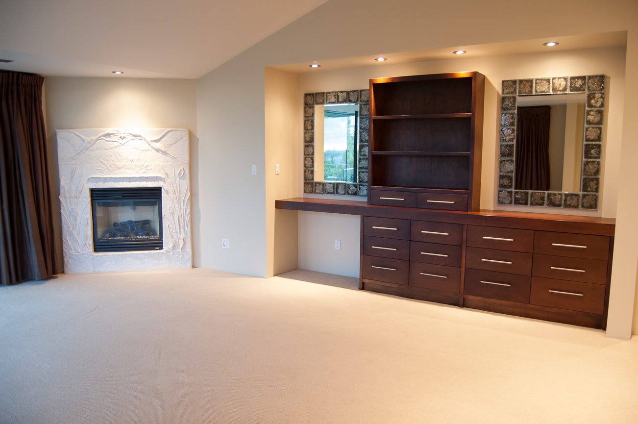 Furnished bedroom with built-in storage, fireplace, and large windows. - 4454 Regency Place, West Vancouver