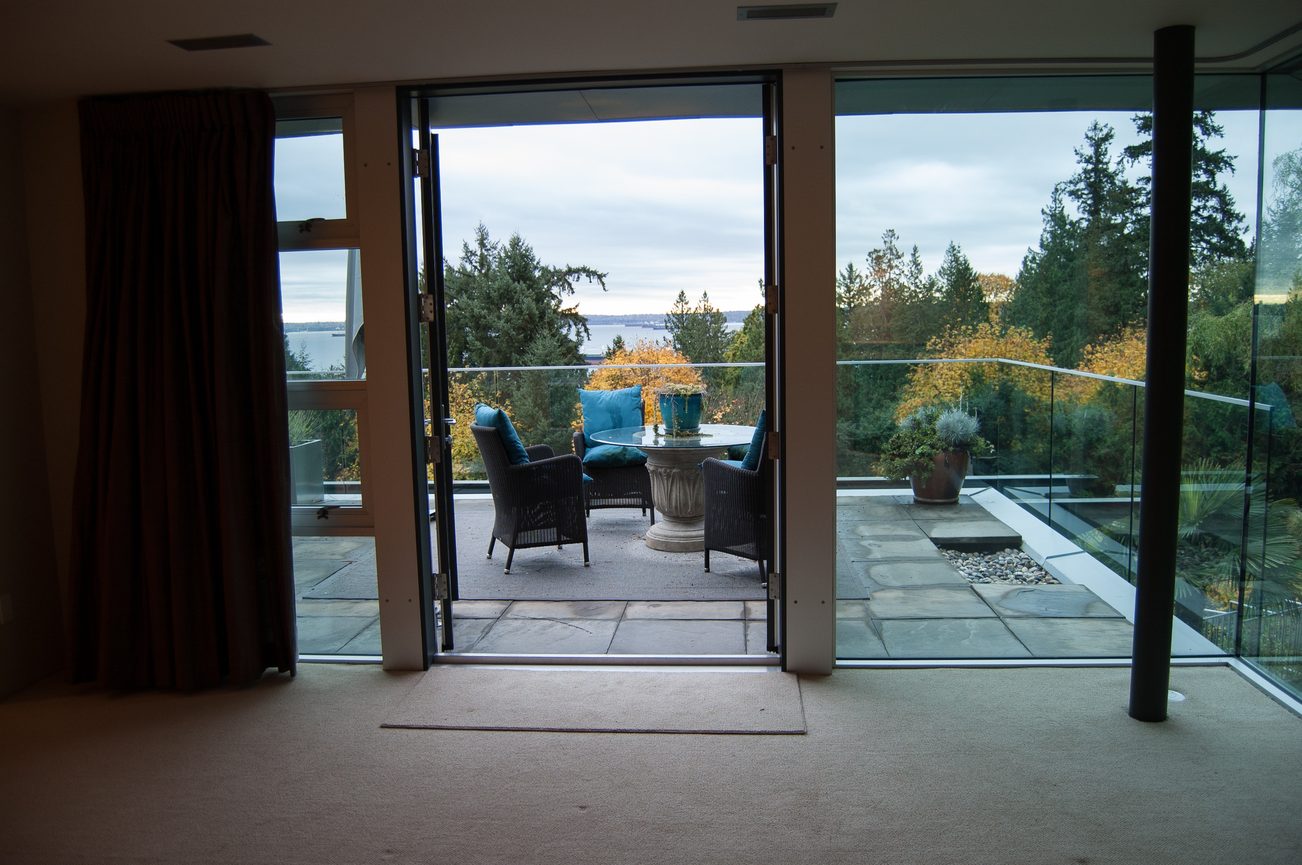 Furnished living room with large glass doors opening to a scenic balcony view. - 4454 Regency Place, West Vancouver