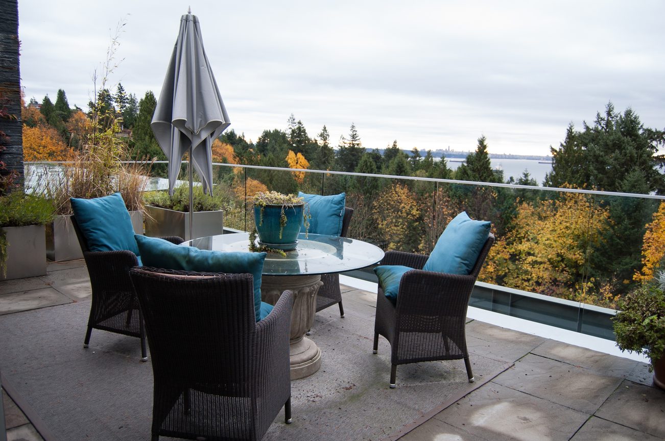 Furnished balcony with glass table, wicker chairs, and city view. - 4454 Regency Place, West Vancouver