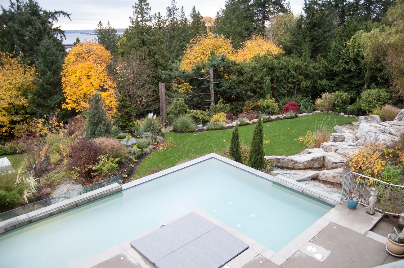 Spacious backyard with infinity pool and lush garden, surrounded by trees. - 4454 Regency Place, West Vancouver