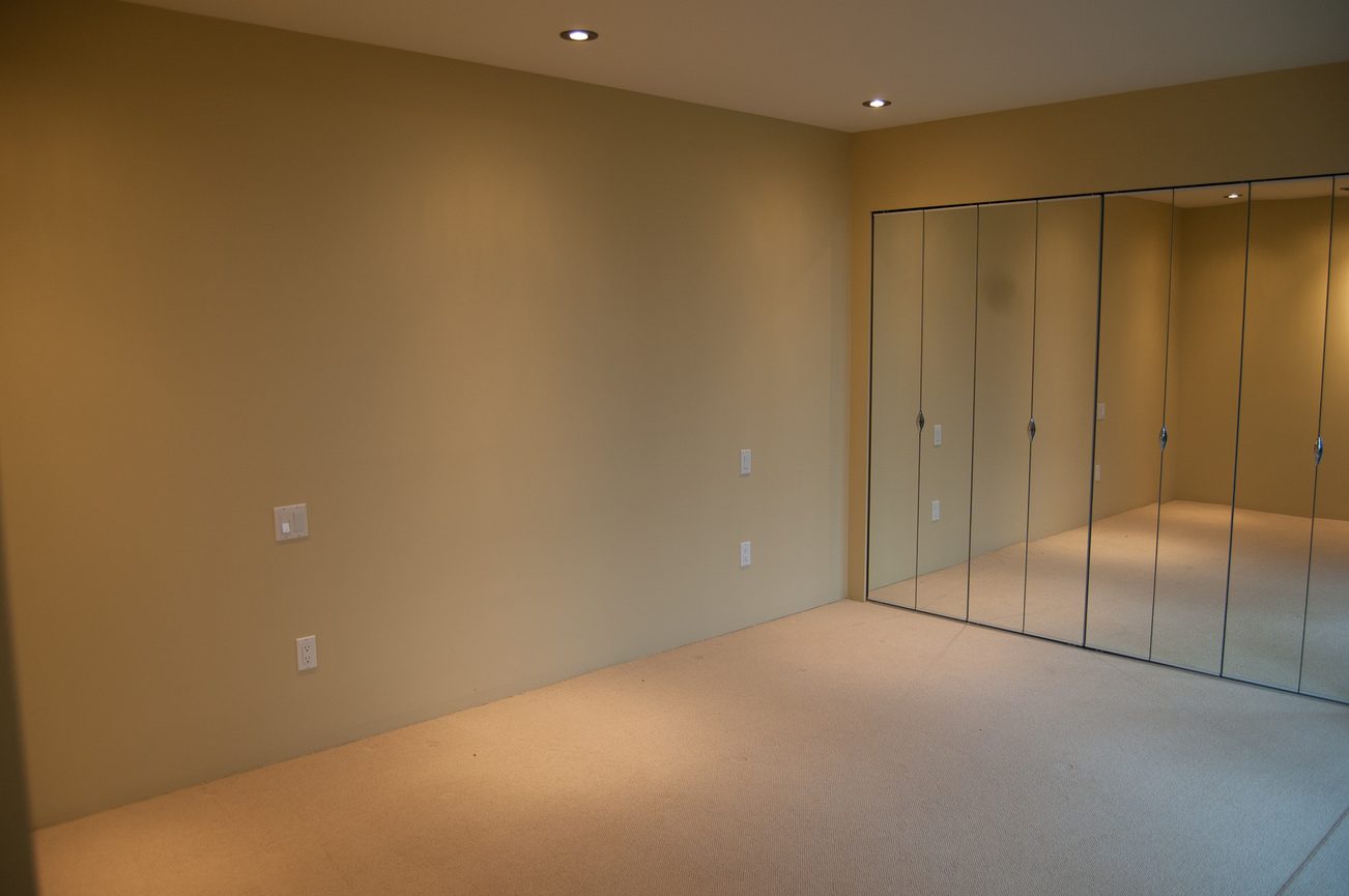 Empty bedroom with carpeted floor and mirrored closet doors. - 4454 Regency Place, West Vancouver
