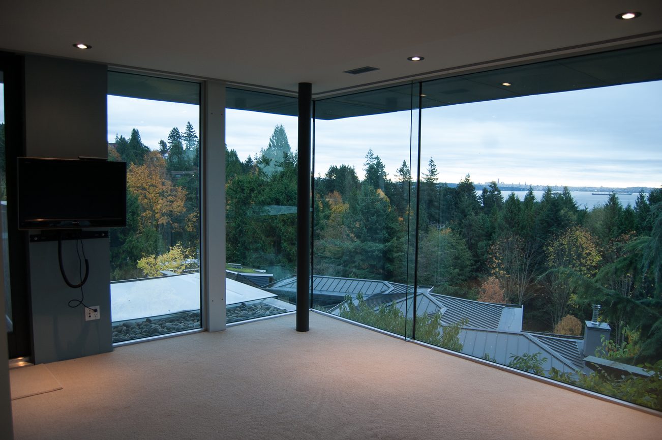 Spacious living room with floor-to-ceiling windows, city view, and modern furnishings. - 4454 Regency Place, West Vancouver