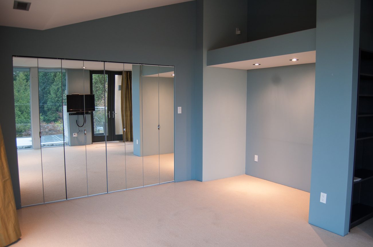 Spacious living room with large glass doors, modern design, and carpeted floors. - 4454 Regency Place, West Vancouver