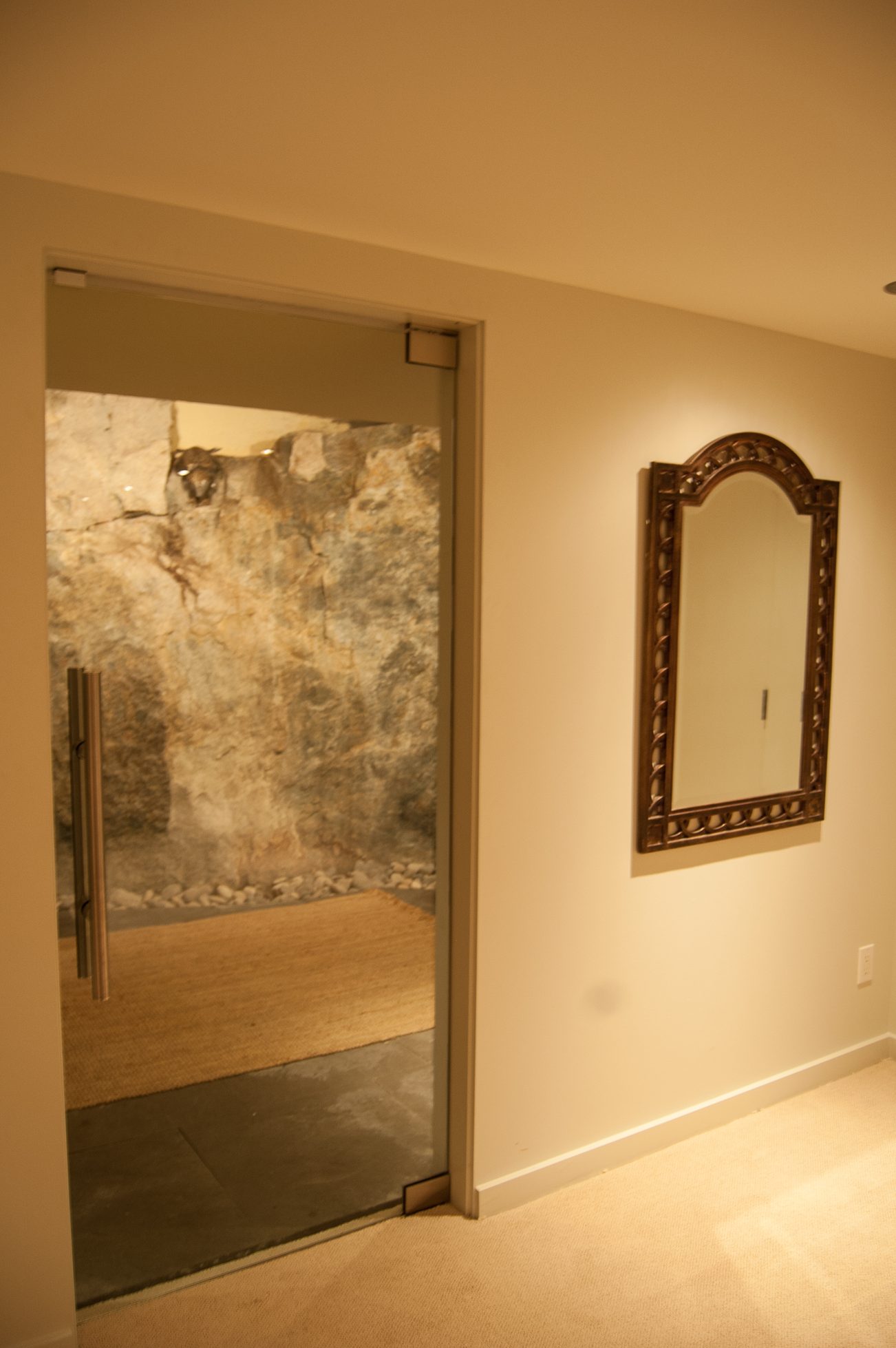 Bright hallway leading to a stone-walled shower, framed mirror on the wall. - 4454 Regency Place, West Vancouver