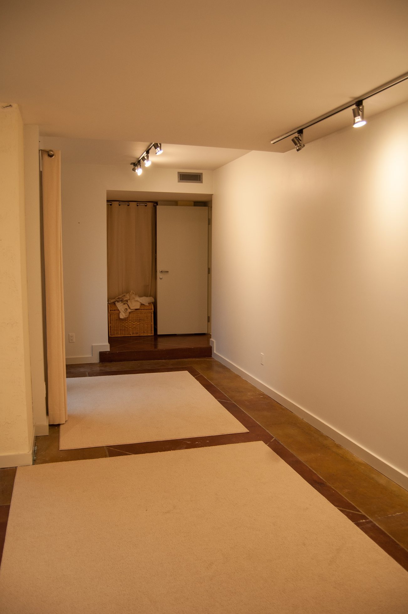 Entryway with carpeted floor and track lighting leading to a door with a wicker basket. - 4454 Regency Place, West Vancouver