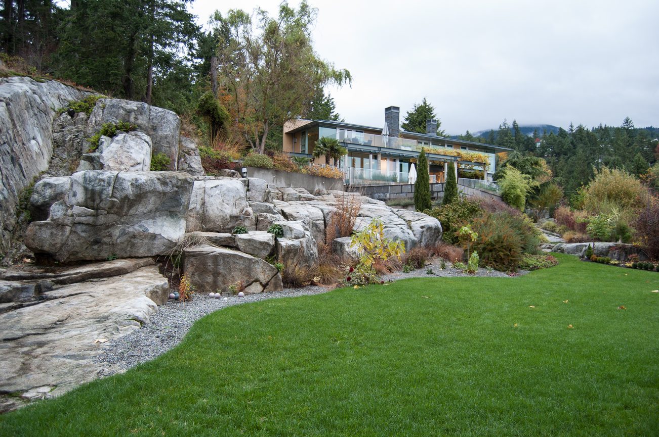 Spacious backyard with rock formations and lush green lawn. - 4454 Regency Place, West Vancouver
