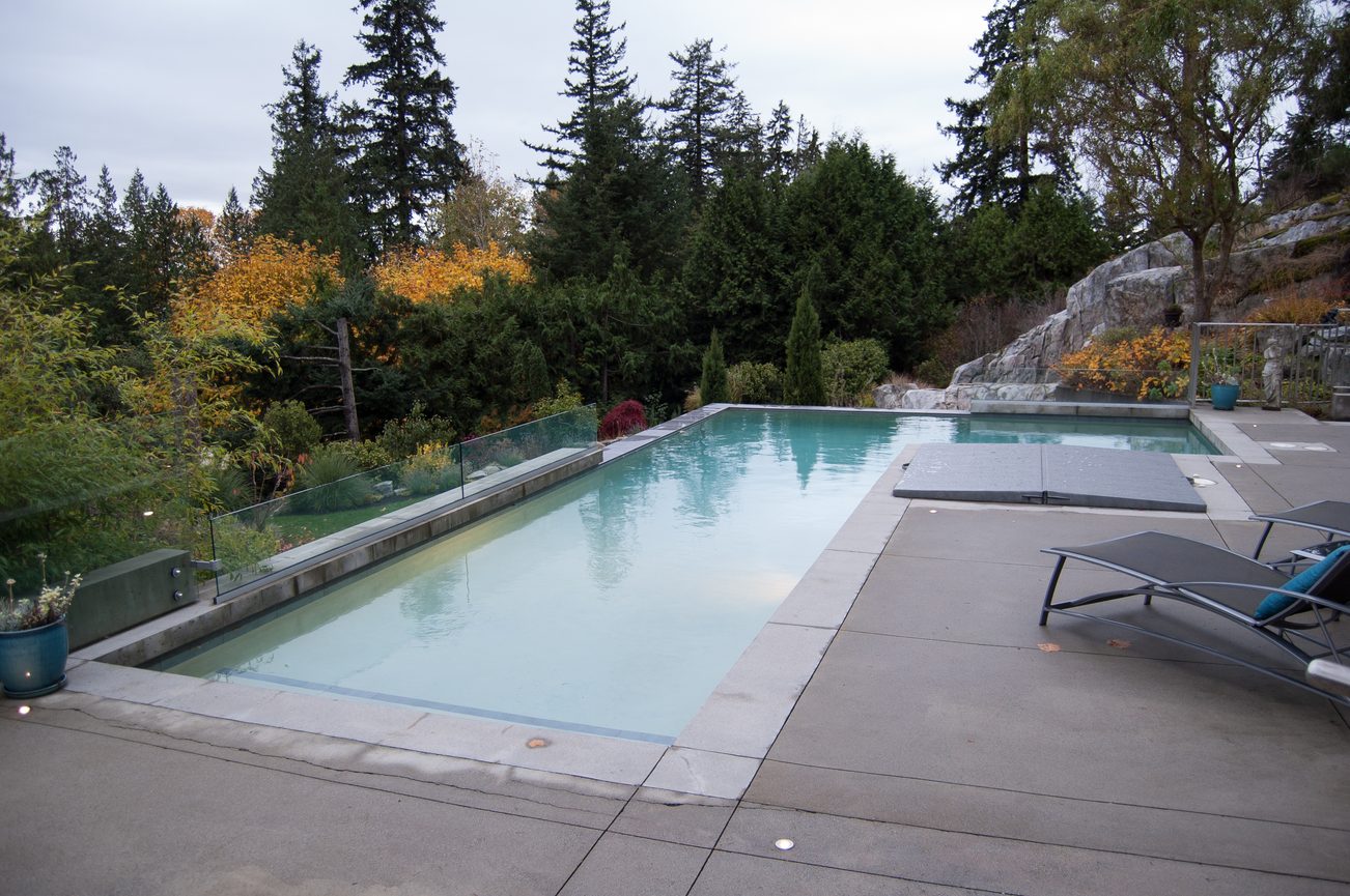 Spacious patio with modern infinity pool and outdoor seating, surrounded by lush greenery. - 4454 Regency Place, West Vancouver