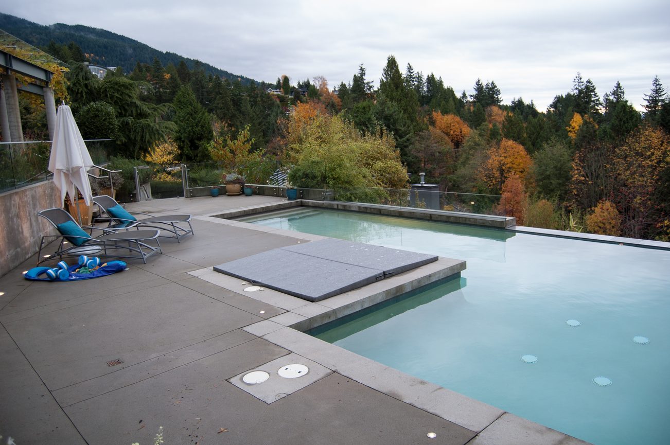 Spacious rooftop pool area with modern lounge chairs and stunning mountain view. - 4454 Regency Place, West Vancouver