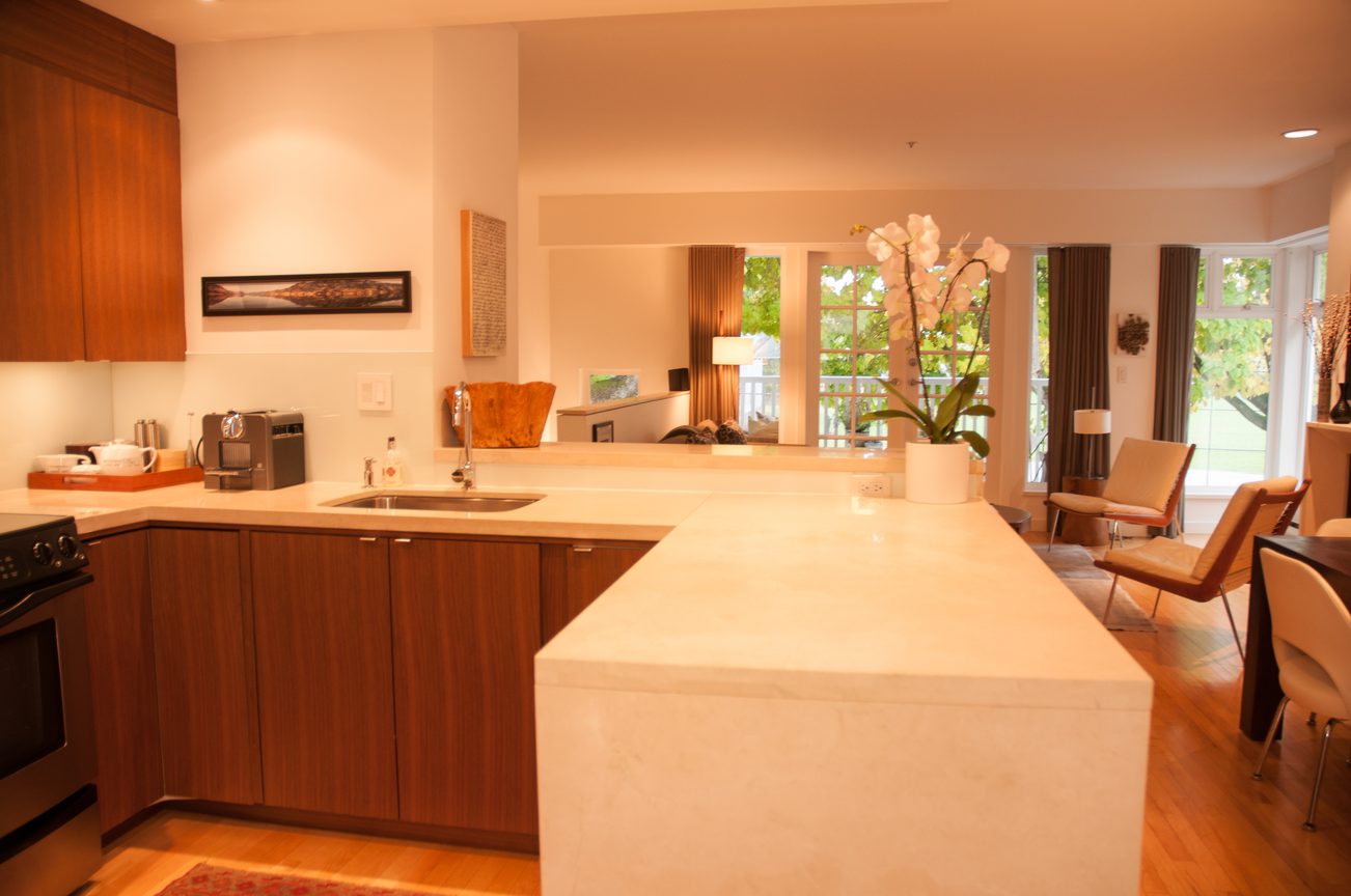 Bright kitchen with white countertops and wooden cabinets, hardwood floors, and a view of the garden. - 7-2305 West 10th Ave, Vancouver West Side