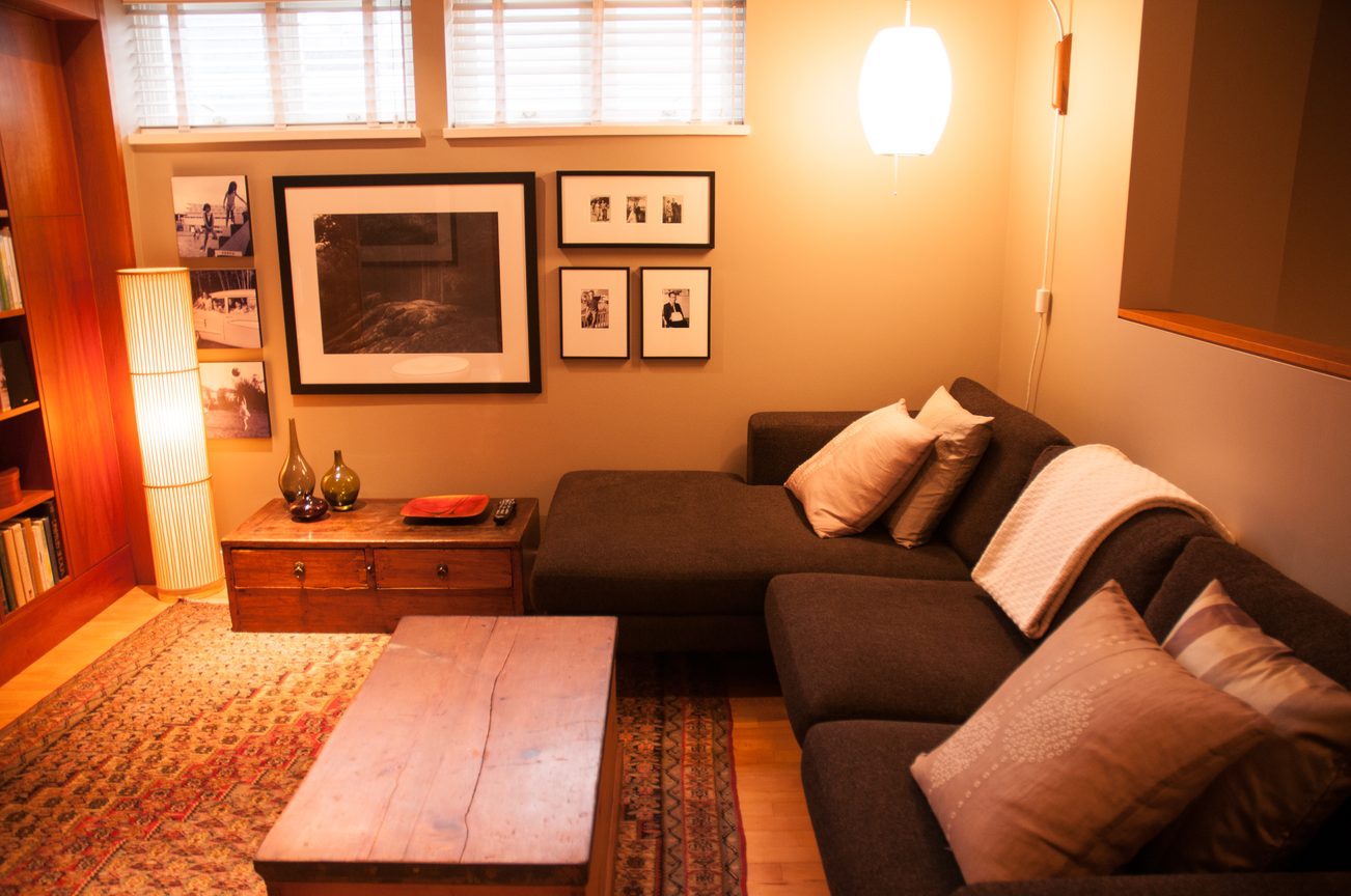 Furnished living room with dark couch, wooden coffee table, and framed artwork on the wall. - 7-2305 West 10th Ave, Vancouver West Side