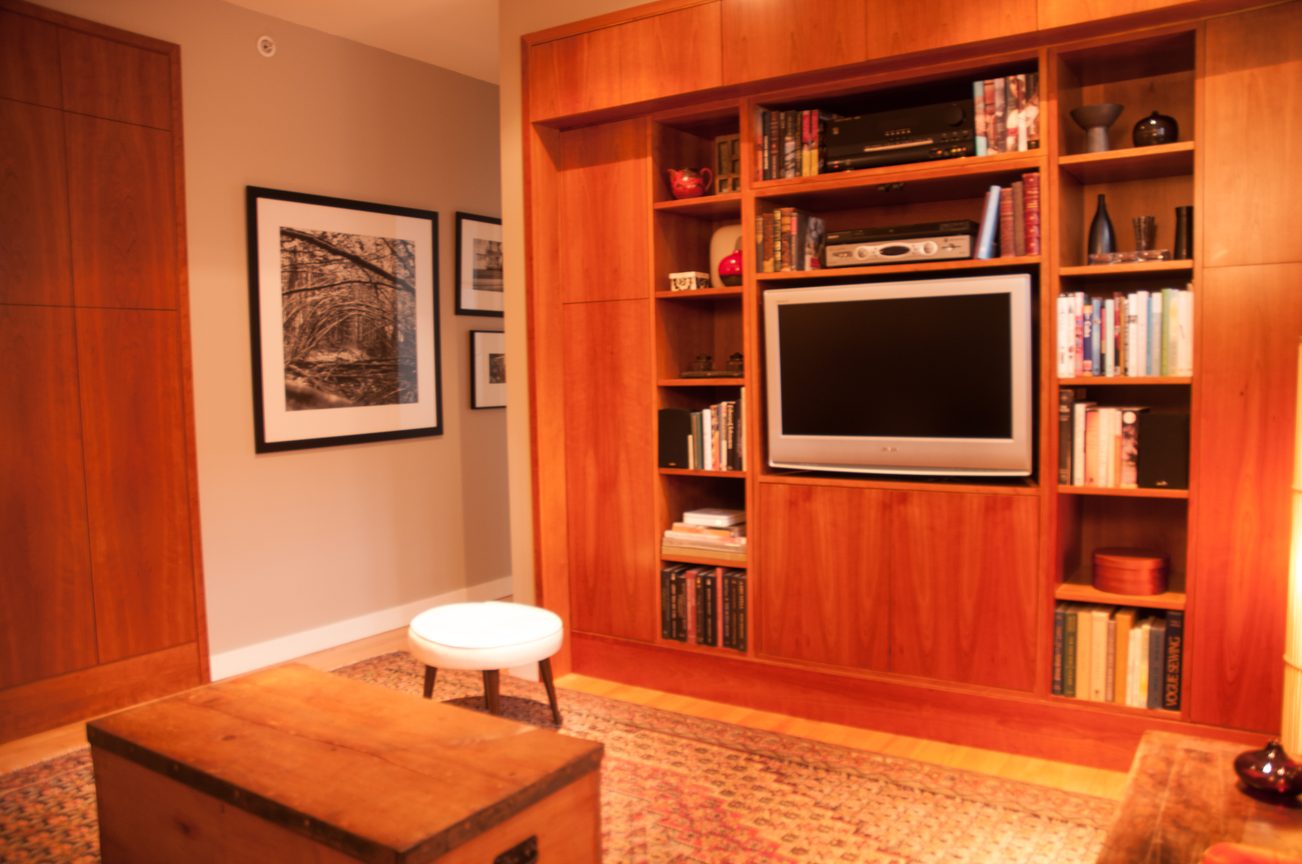 Living room with built-in entertainment center, wooden furniture, and framed artwork. - 7-2305 West 10th Ave, Vancouver West Side