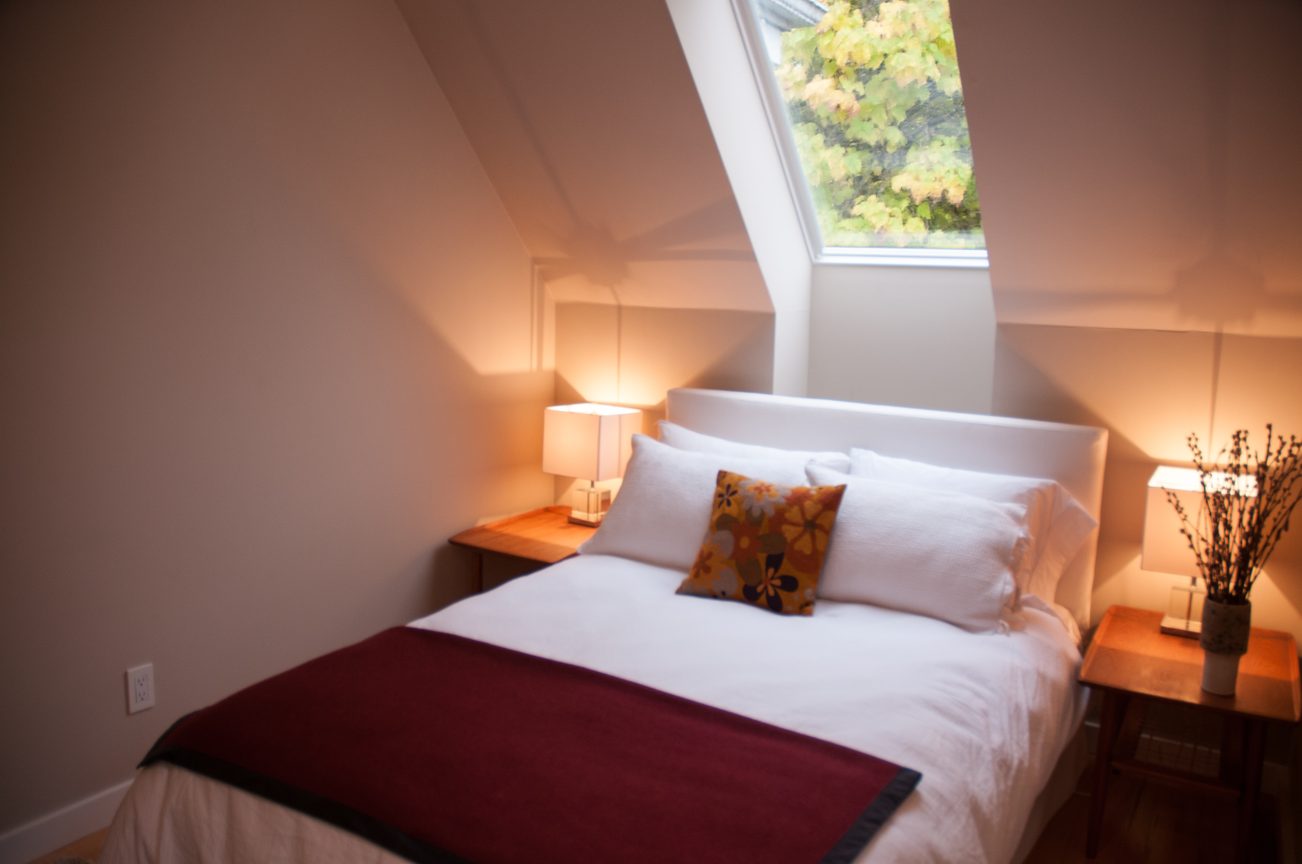Furnished bedroom with cozy bedding, wooden nightstands, and a skylight view of greenery. - 7-2305 West 10th Ave, Vancouver West Side