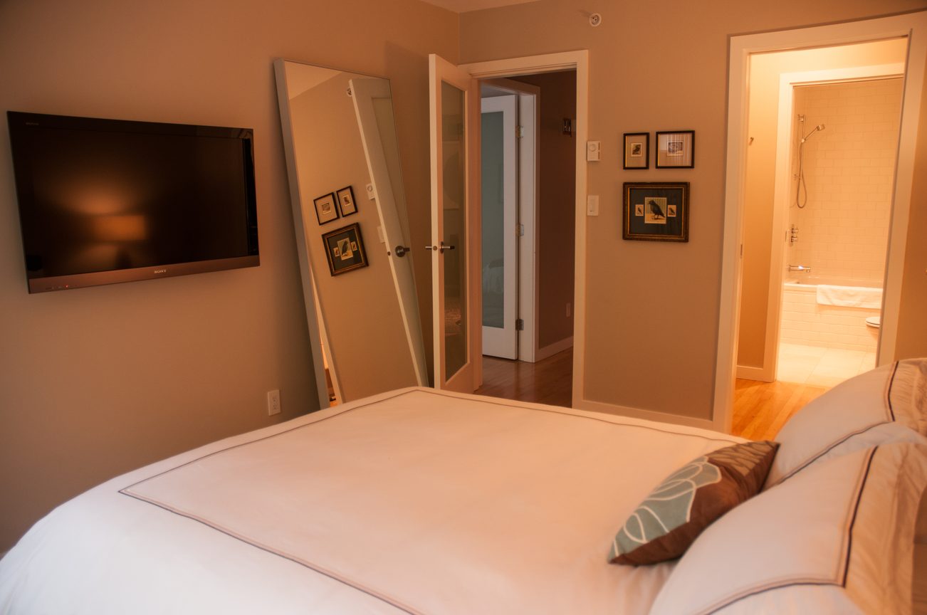 Furnished bedroom with hardwood floors and a large mirror leaning against the wall. - 7-2305 West 10th Ave, Vancouver West Side