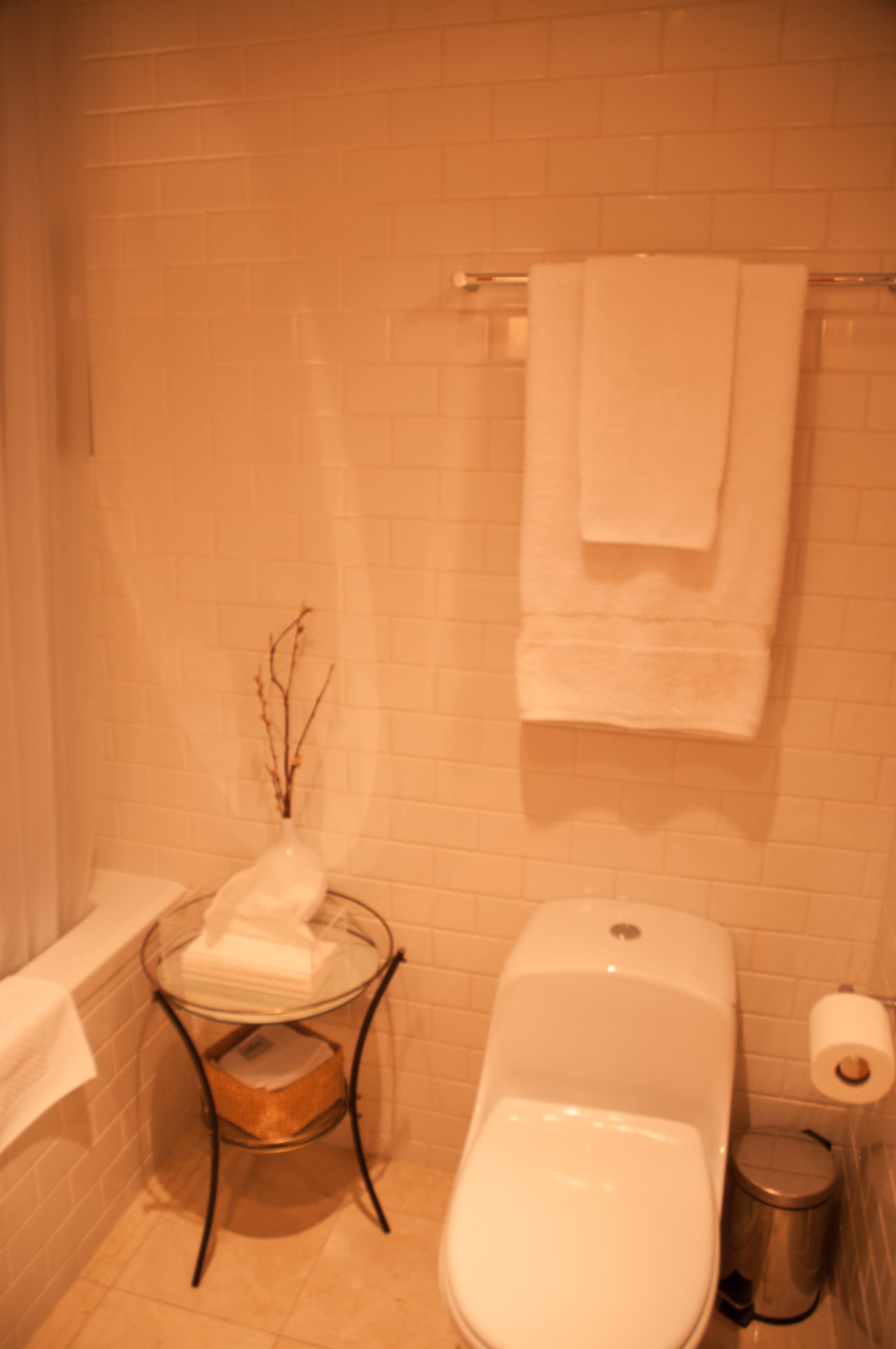 Furnished bathroom with white towels and a glass table holding folded towels and a vase. - 7-2305 West 10th Ave, Vancouver West Side