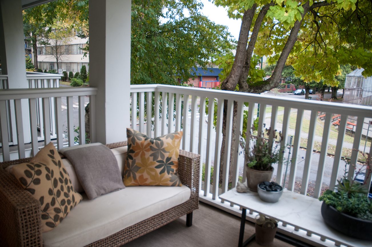 Furnished balcony with wicker furniture, cushions, and potted plants, overlooking trees and a street view. - 7-2305 West 10th Ave, Vancouver West Side