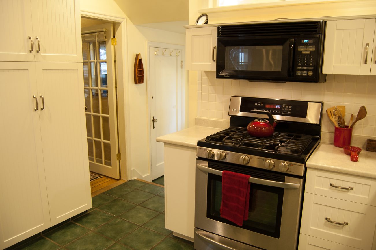Bright kitchen with white cabinets, green tile floor, and stainless steel appliances. - 139 Osbourne Rd. East, North Vancouver