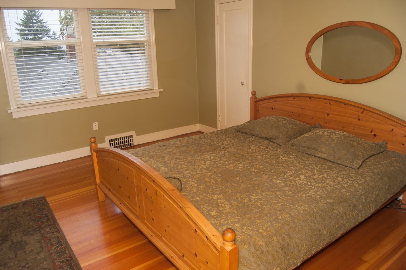 Furnished bedroom with wooden bed frame and hardwood floors. - 139 Osbourne Rd. East, North Vancouver