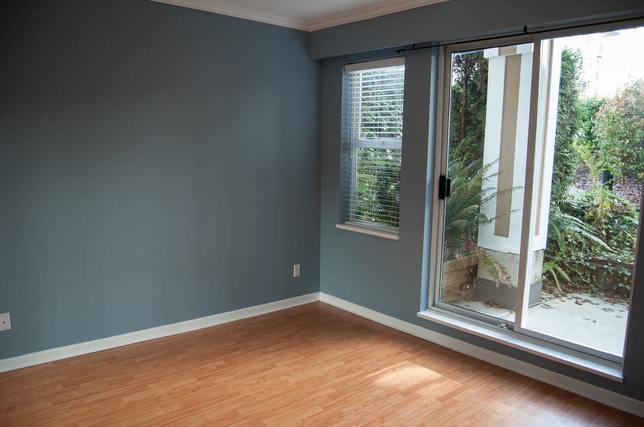 Bright living room with hardwood floors and sliding glass door leading to a garden view. - 232 - 3629 Deercrest Dr, North Vancouver