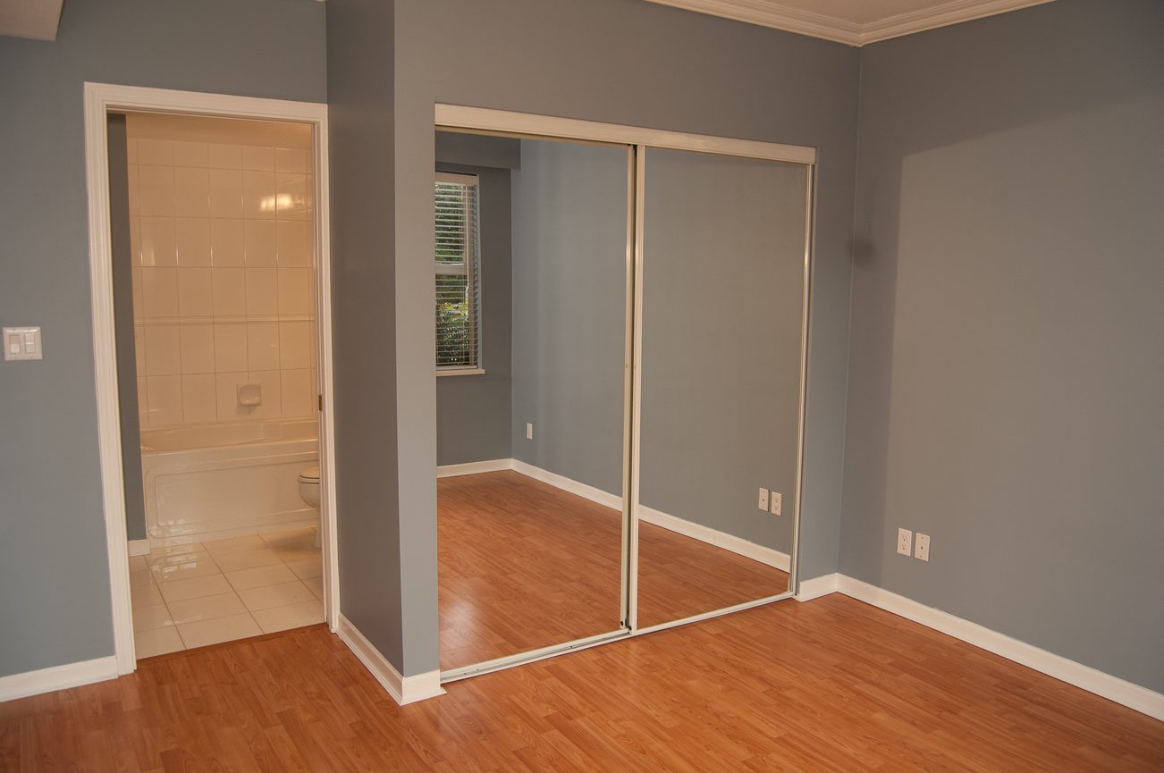 Bright living room with hardwood floors and sliding glass doors leading to a bathroom. - 232 - 3629 Deercrest Dr, North Vancouver