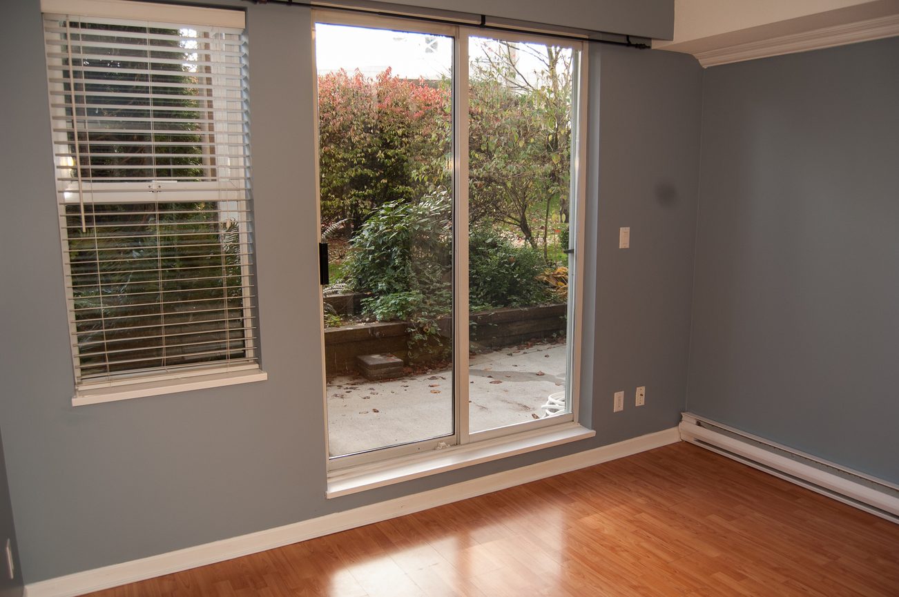 Bright living room with hardwood floors and sliding glass door leading to a garden. - 232 - 3629 Deercrest Dr, North Vancouver