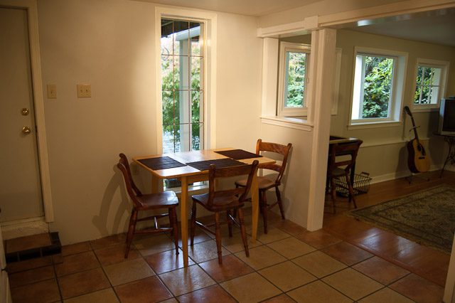 Bright dining area with wooden table and chairs, natural light from large windows, hardwood floors. - 139 Osbourne Rd. East, North Vancouver