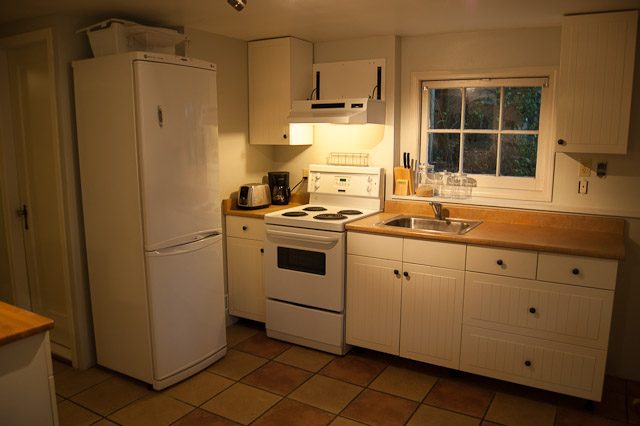 Bright kitchen with white cabinets, tiled floor, and a window view. - 139 Osbourne Rd. East, North Vancouver