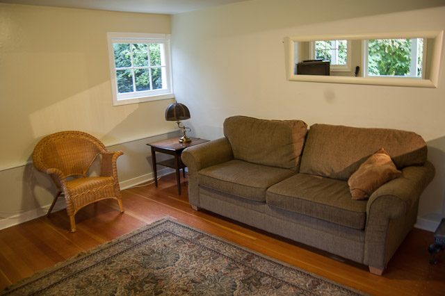 Bright living room with hardwood floors, wicker chair, and patterned rug. - 139 Osbourne Rd. East, North Vancouver