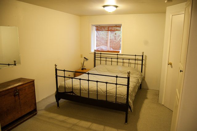 Furnished 1-bedroom suite with a metal bed frame and a small dresser. - 139 Osbourne Rd. East, North Vancouver
