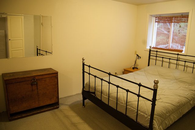 Furnished bedroom with metal bed frame and wooden dresser. - 139 Osbourne Rd. East, North Vancouver