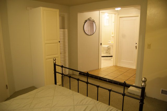 Bright bedroom with white walls, wooden closet, and bathroom access. - 139 Osbourne Rd. East, North Vancouver
