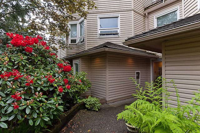 Furnished 2-bedroom condo with red flowers and wooden fencing. - 106-827 West 16th Street, North Vancouver