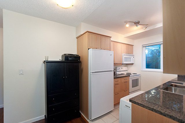 Bright kitchen with granite countertops, hardwood floors, and a city view. - 106-827 West 16th Street, North Vancouver