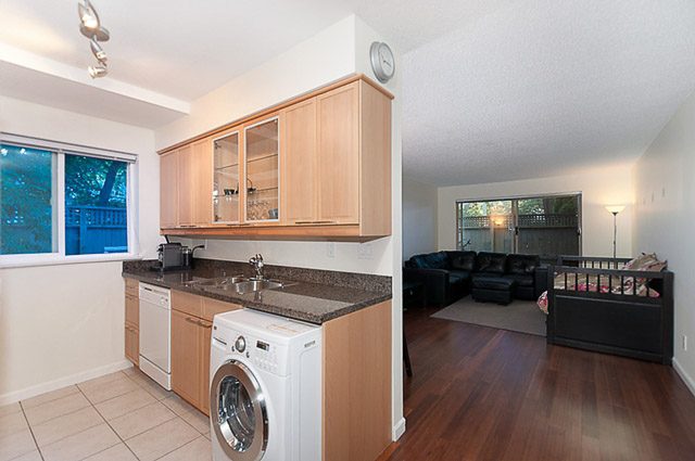 Bright kitchen with granite countertops and hardwood floors, leading to a cozy living area with a city view.