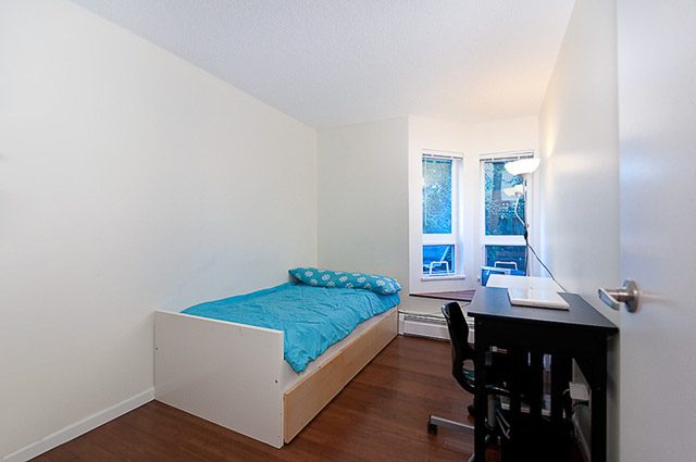 Bright bedroom with hardwood floors, city view, and a desk. - 106-827 West 16th Street, North Vancouver