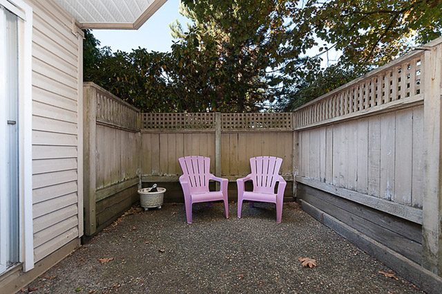Furnished patio with pink chairs and wooden railings. - 106-827 West 16th Street, North Vancouver