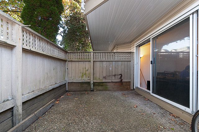 Furnished patio with sliding glass doors and wooden fencing. - 106-827 West 16th Street, North Vancouver