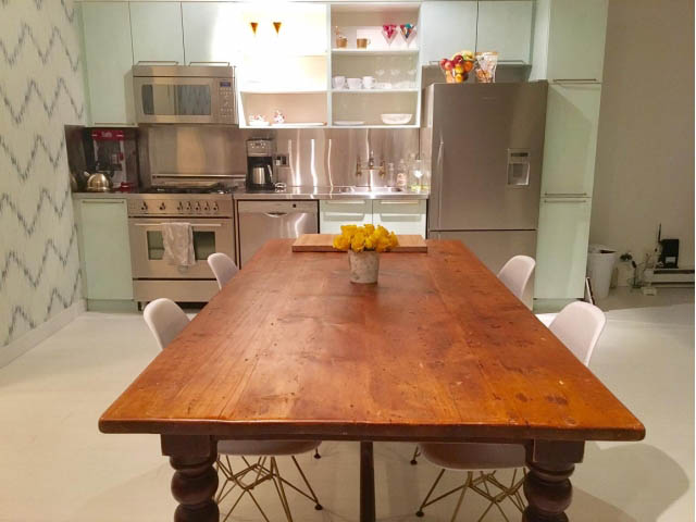 Bright kitchen with stainless steel appliances and a rustic wooden dining table. - 410 - 1072 Hamilton Street, Vancouver Downtown