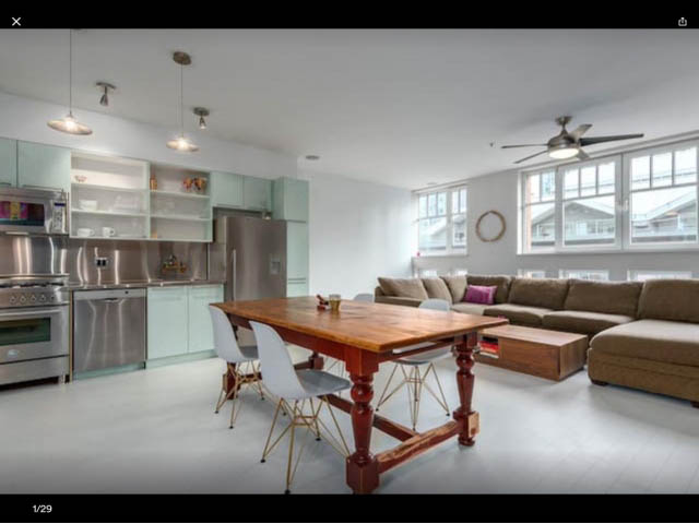Bright kitchen with stainless steel appliances and light green cabinets, open-concept living area with modern furniture...