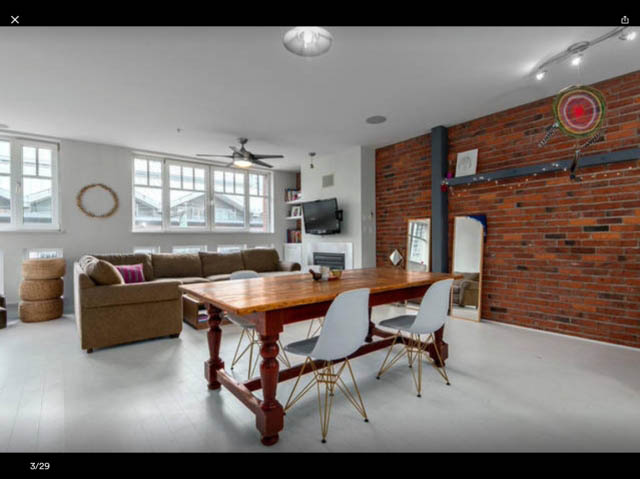 Furnished living room with brick accent wall, hardwood floors, and large windows. - 410 - 1072 Hamilton Street, Vancouver Downtown