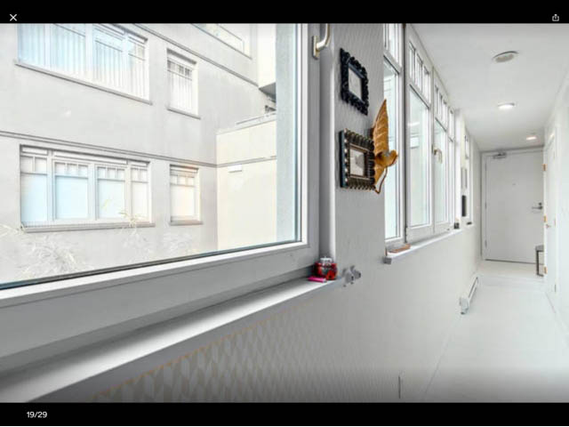 Bright living room with large windows and white walls, showcasing a city view. - 410 - 1072 Hamilton Street, Vancouver Downtown