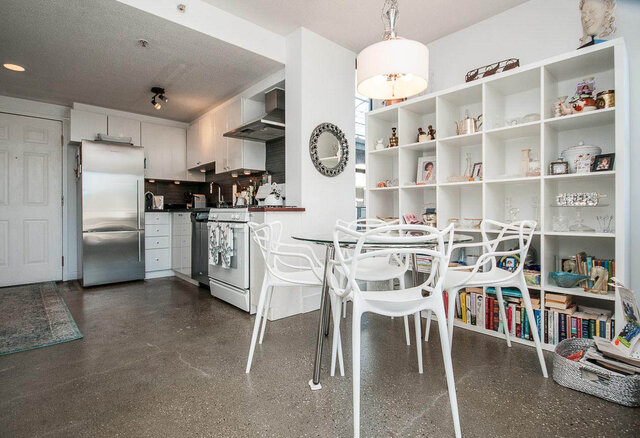 Open-concept kitchen and dining area with white cabinetry, stainless steel appliances, and a modern dining set.