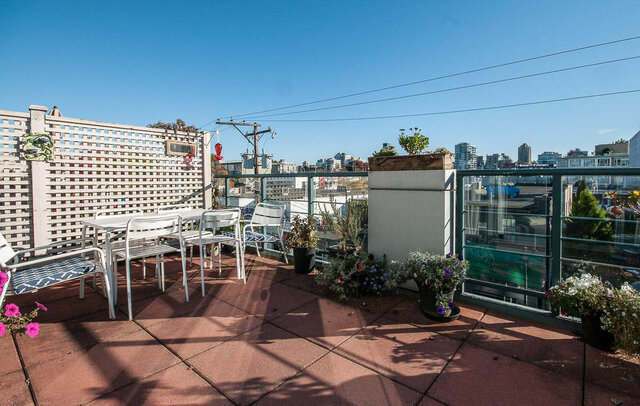 Furnished balcony with a city view, cozy seating, and vibrant flower pots. - 312 - 1630 West 1st Ave., Vancouver West Side
