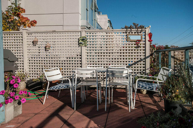 Furnished patio with white chairs, lattice wall, and potted flowers. - 312 - 1630 West 1st Ave., Vancouver West Side