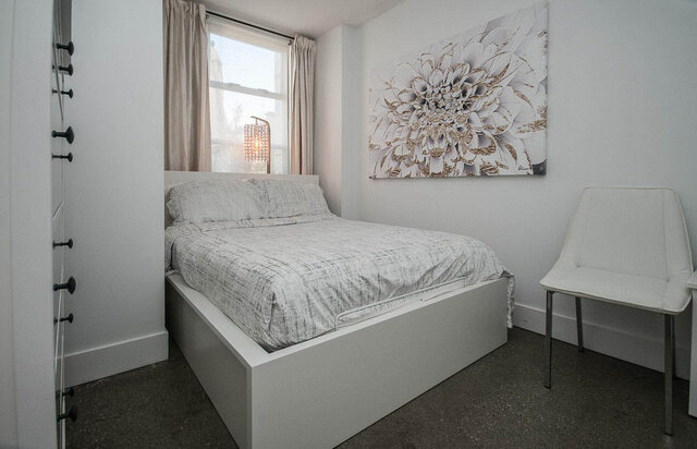Spacious 1-bedroom condo with modern white furniture, a large floral wall art, and a cozy window seat. - 312 - 1630 West 1st Ave., Vancouver West Side