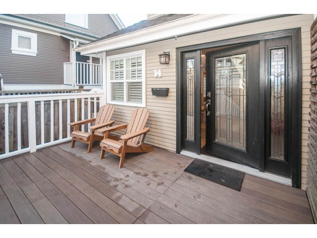 Furnished deck with wooden chairs and black door, leading to a house. - 14 West 13th Ave, Vancouver East Side